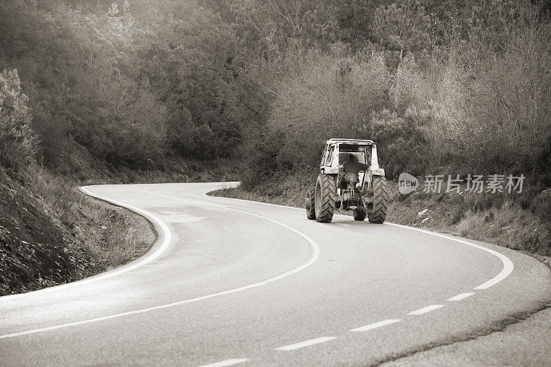 开着拖拉机沿着蜿蜒的乡村道路行驶。