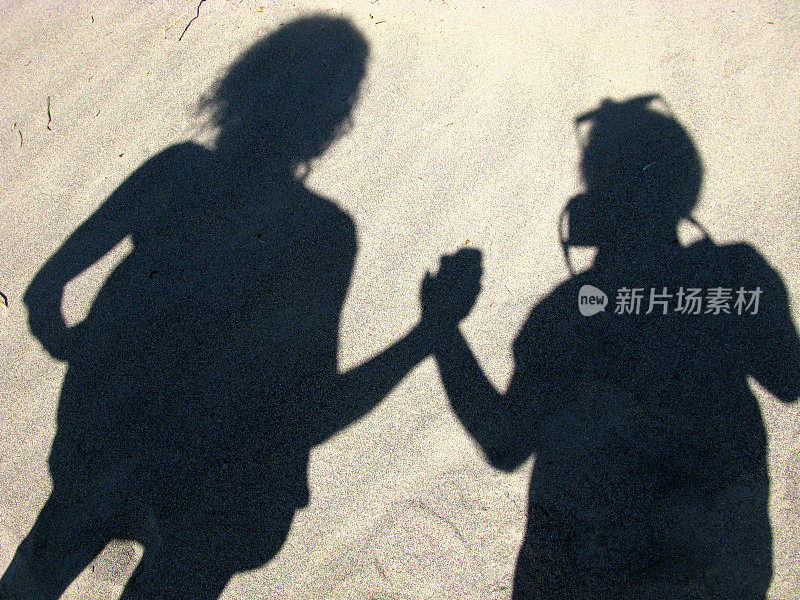 母亲和女儿手牵着手沙上的影子
