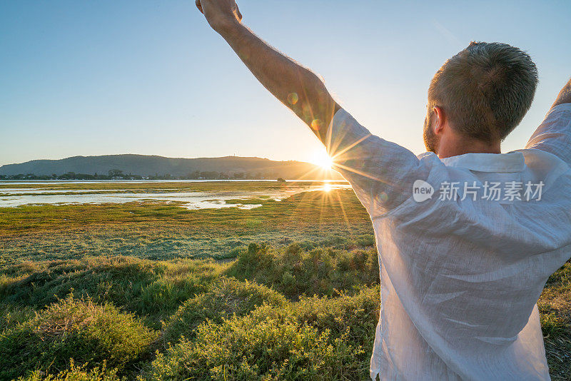 年轻人在海边放松，伸开双臂