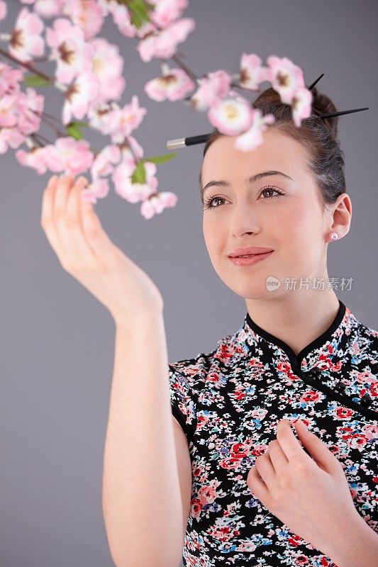 年轻女子在亚洲服装触摸鲜花