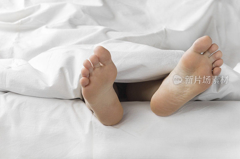 清晨，女人的脚在白色的被褥上