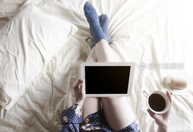 女人躺在床上，拿着药片，喝着咖啡