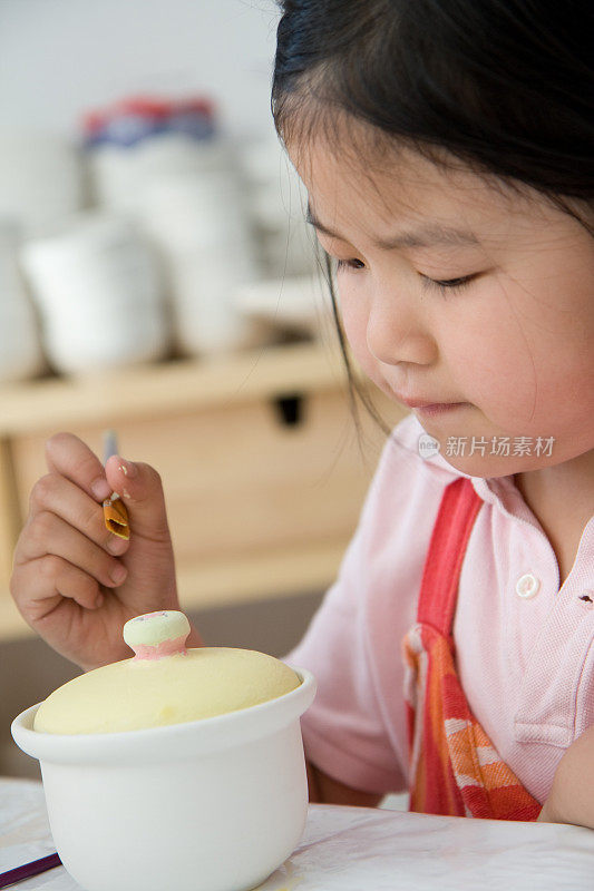 年轻的女孩用颜料在陶罐上作画