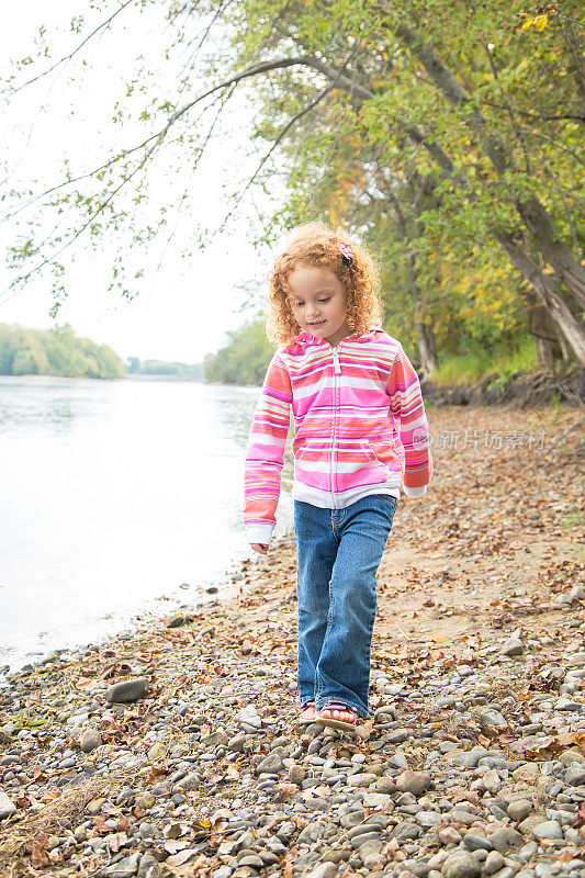 沿着河岸走的年轻女孩的正面视图