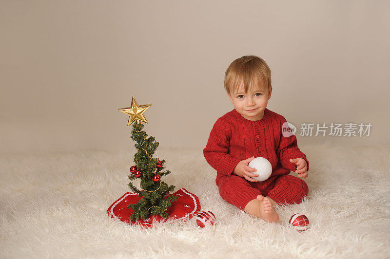 可爱微笑的小男孩坐在圣诞树旁