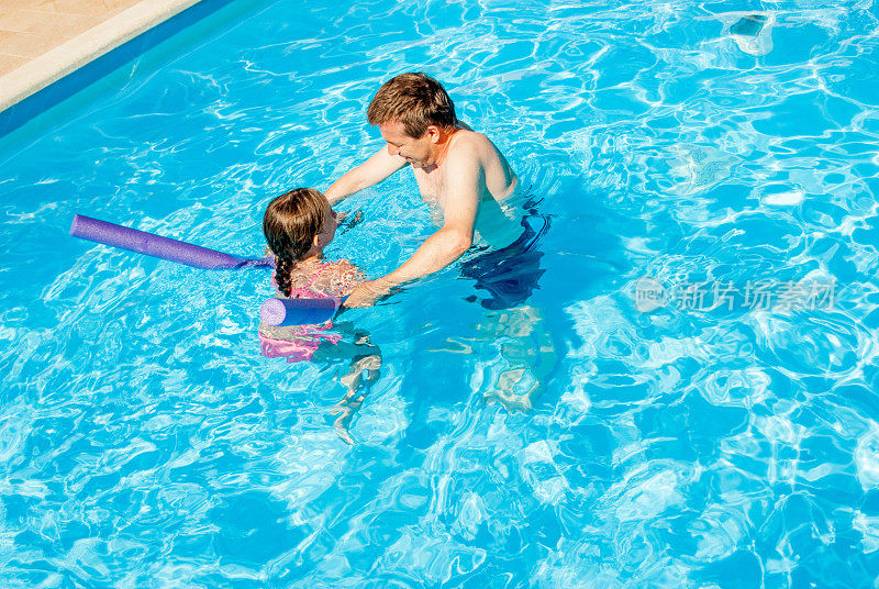 爸爸在游泳池教女儿游泳