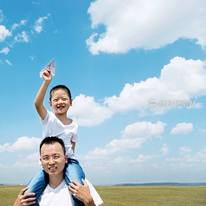 儿子和父亲在田野里玩纸飞机