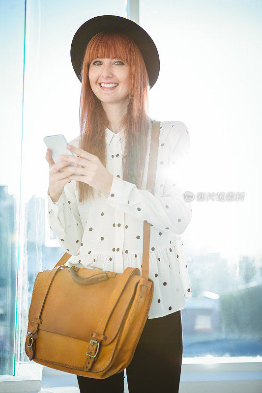 微笑的时髦女人用她的智能手机发短信
