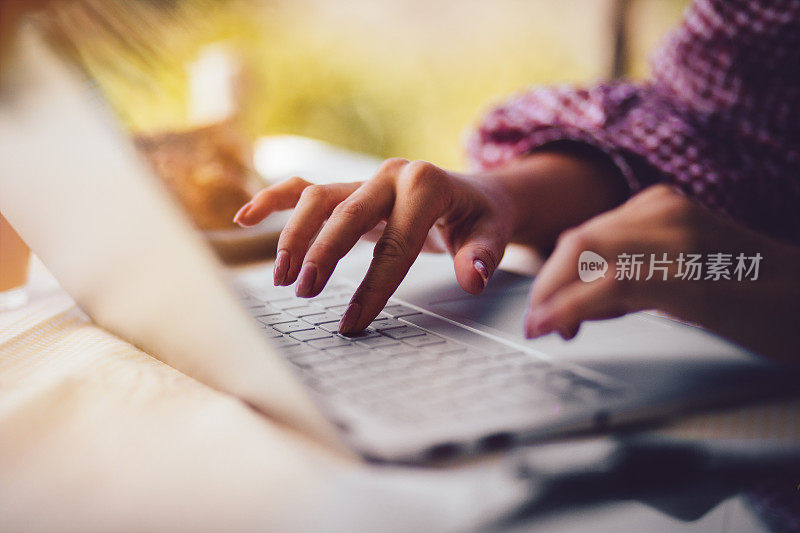 女人的手在笔记本电脑键盘上打字的特写