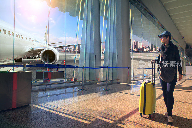 旅行的女人和行李走在机场航站楼和飞机飞行外面