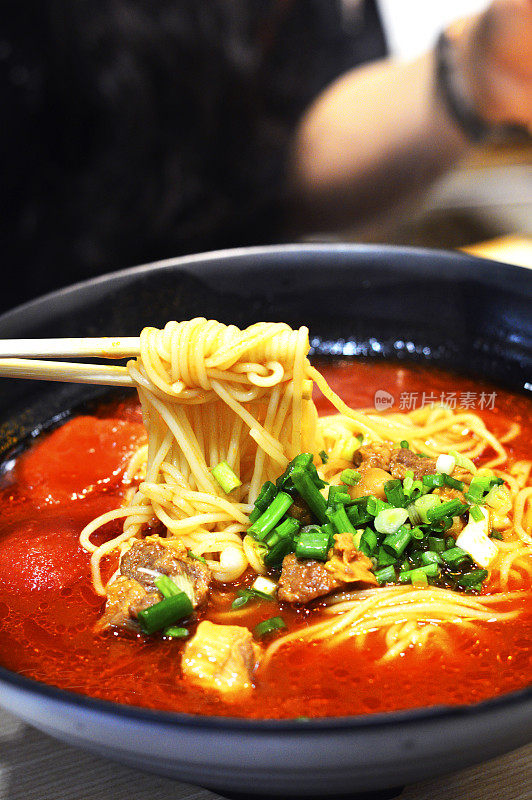 筷子从大碗里夹起中国番茄牛肉面