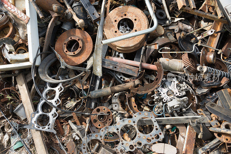 旧的生锈的汽车零件在汽车报废场。汽车回收。拆卸机械部件等待再利用或作为维修部件。