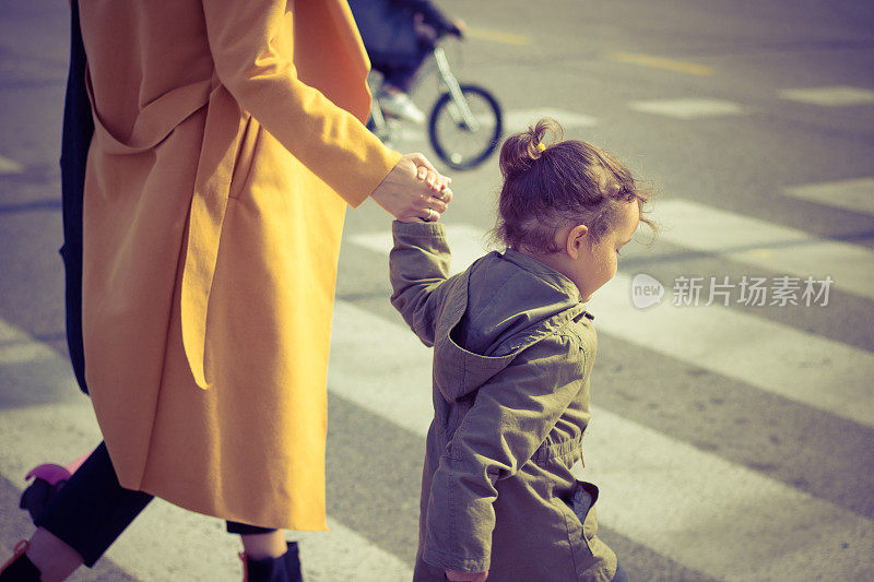 小女孩和妈妈一起过马路。