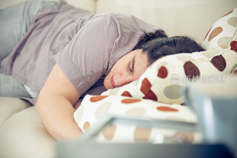 年轻疲惫的女人在沙发上打盹