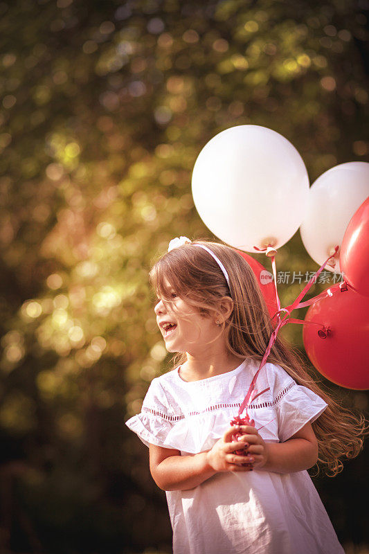 快乐快乐的小女孩与气球在草地上
