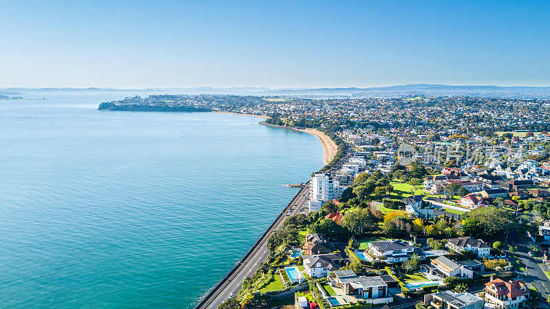 以近郊住宅区为背景的海边公路鸟瞰图。新西兰奥克兰。