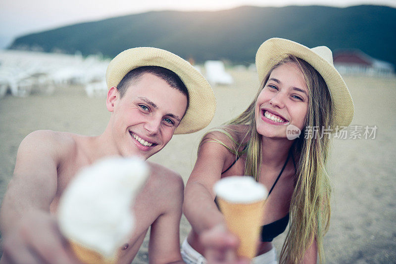 年轻的夫妇在海滩上吃冰淇淋
