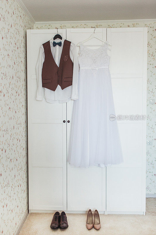 橱柜上挂着新娘的礼服和新郎的礼服