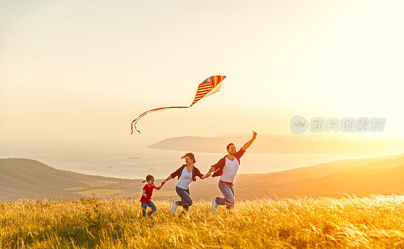幸福的家庭，父亲母亲和孩子的女儿在自然放风筝在日落
