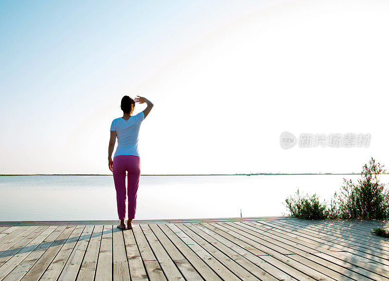 年轻女子在湖边举起双臂