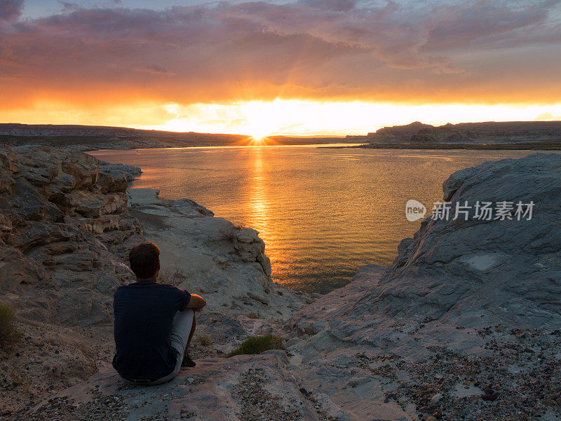 在美国犹他州瓦赫韦普湾鲍威尔湖看日落的年轻人