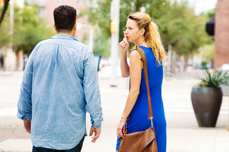 愤怒的女人在城市街道上嘘男同伴