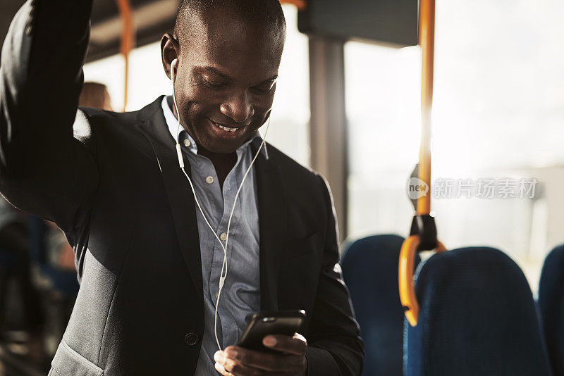 微笑的非洲商人坐在公交车上听着音乐