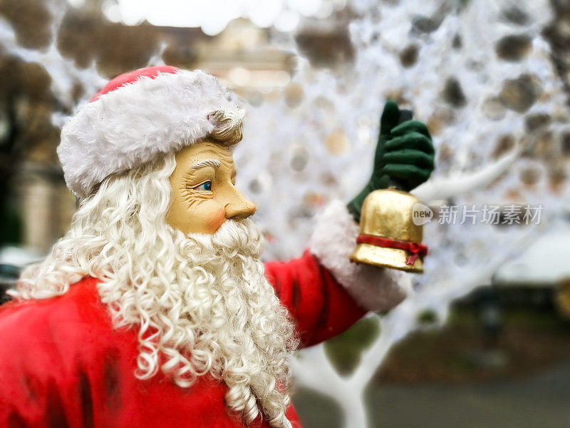 真人大小的圣诞老人在室外举着一个金铃