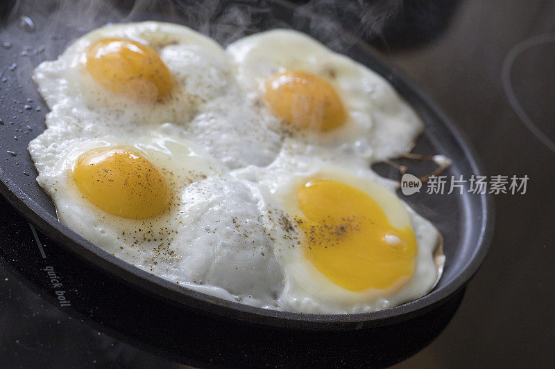 早餐是什么?四个鸡蛋在玻璃陶瓷炉上煮着。