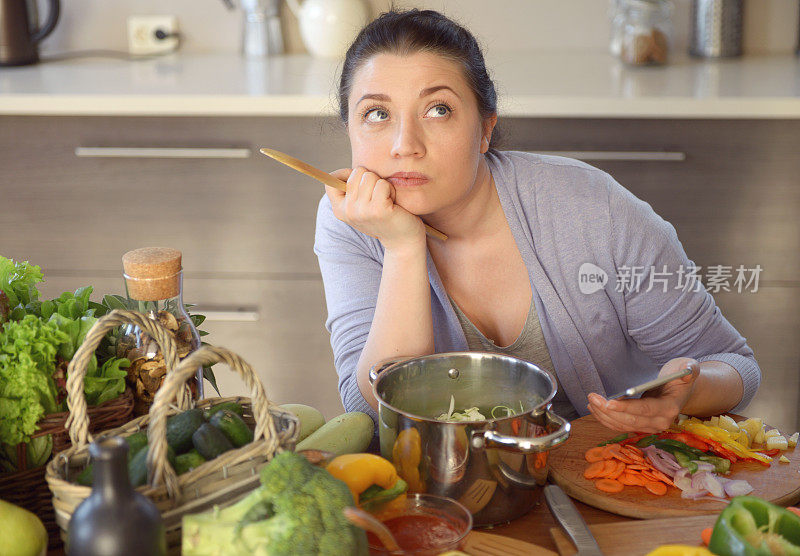 女人在厨房做饭(用智能手机)