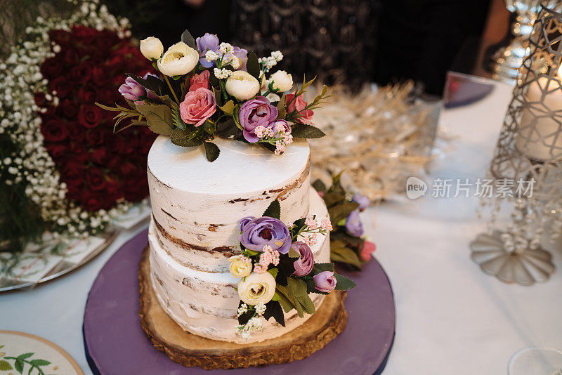 烹饪、甜蜜、婚礼理念。近距离两层神奇的蛋糕与白色和棕色的地毯和装饰鲜花