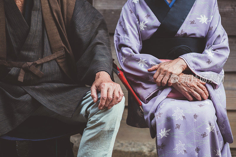 外面坐着一名年长的男女，是日本人的民族，穿着和服，江户时代