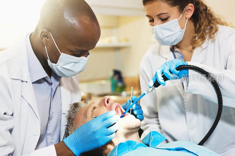 牙医和他的助手正忙着接待一位男病人