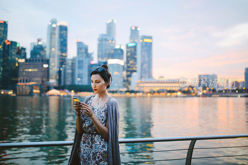 年轻时尚的女游客在新加坡看她的智能手机