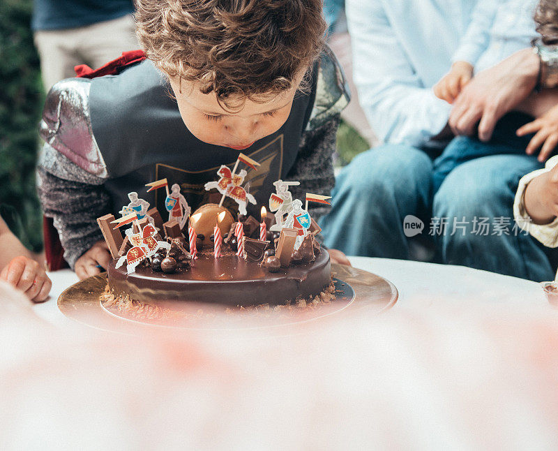 男孩在他的生日派对上吹蜡烛