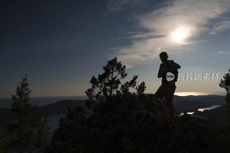 克罗地亚Mljet岛的大湖上，老妇人背对着太阳行走的影子