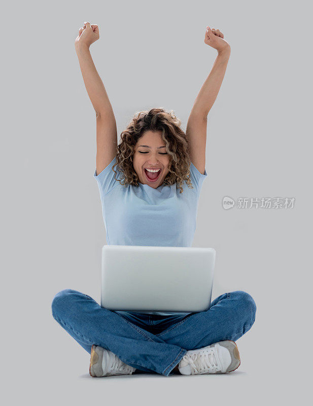 快乐的女人在网上工作，手举着手庆祝