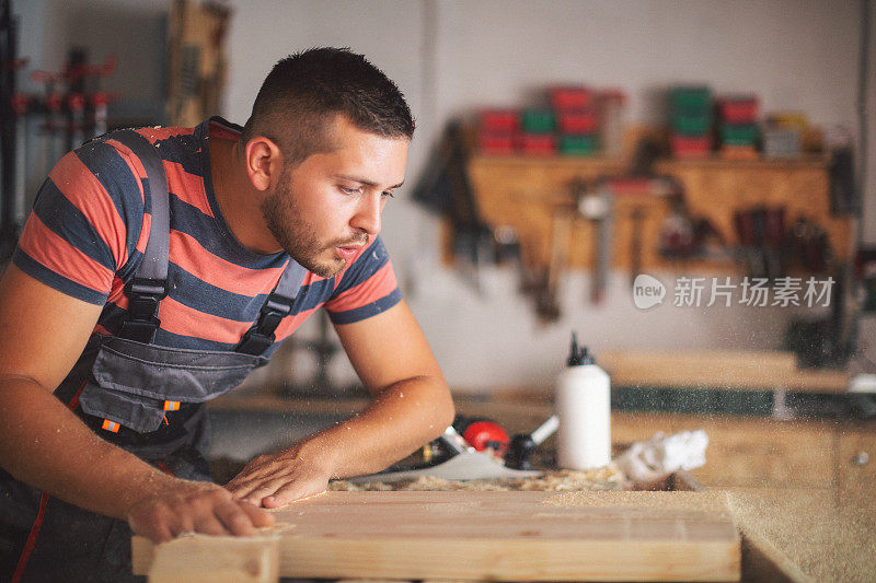 年轻的木匠打磨木制桌面