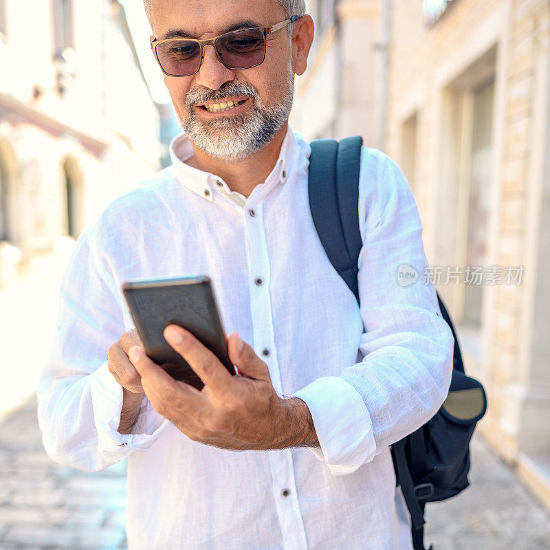 成熟的男人在街上用手机发短信