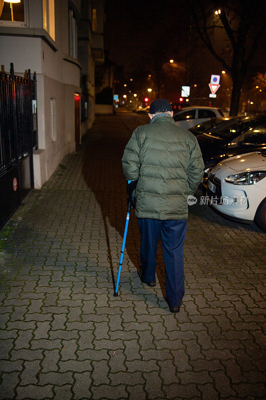 老年人在法国街头使用保持平衡的手杖行走的后视图