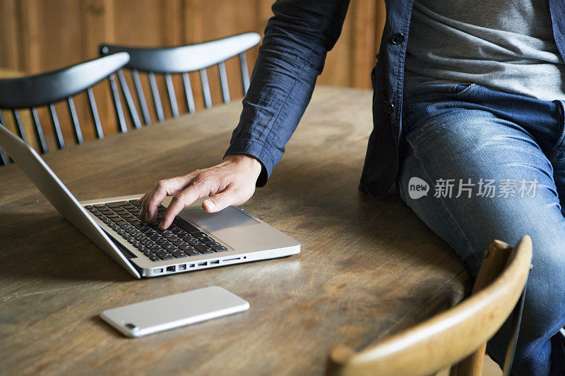 中年人坐在桌子上用笔记本电脑