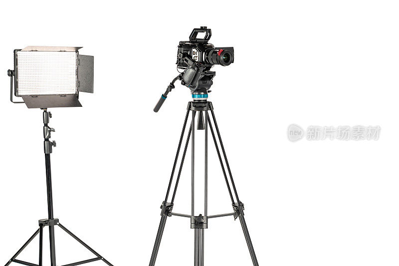 专业视频电影相机在相机三脚架和专业照明灯具在白色工作室背景