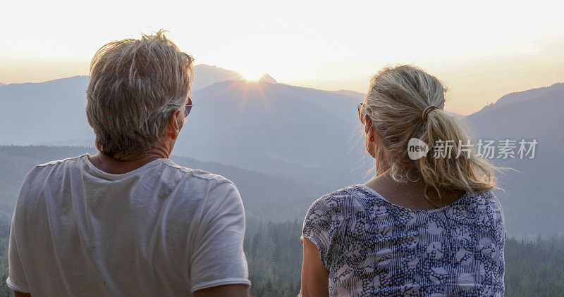 成熟的夫妇在山崖上放松，看外面的景色