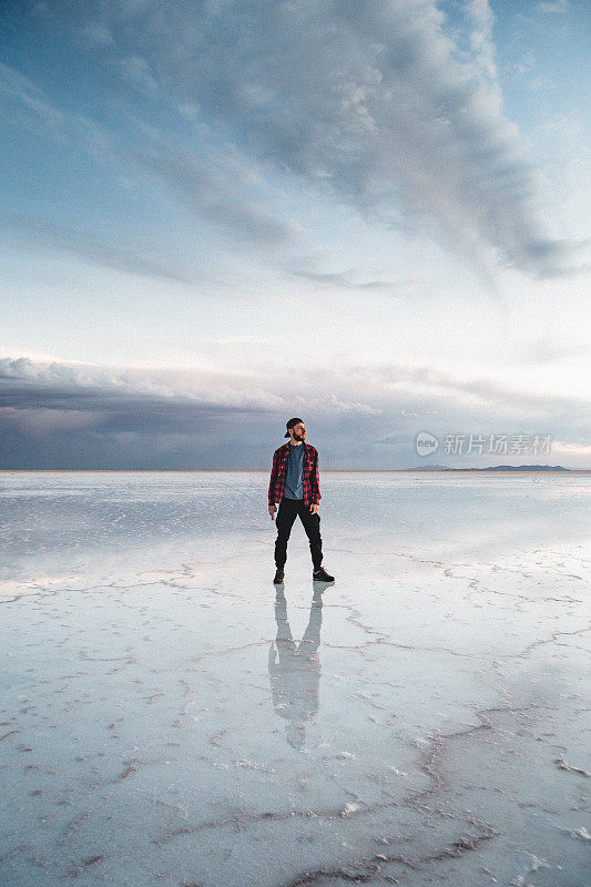 玻利维亚乌尤尼盐湖，一名年轻的白人男子在欣赏日落