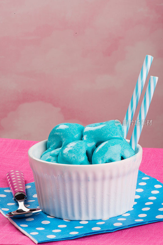 白色的杯子里是蓝天冰淇淋，粉红色的背景上是蓝色的餐巾