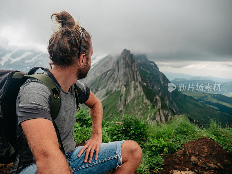 一名男子在瑞士徒步旅行，然后停下来看风景