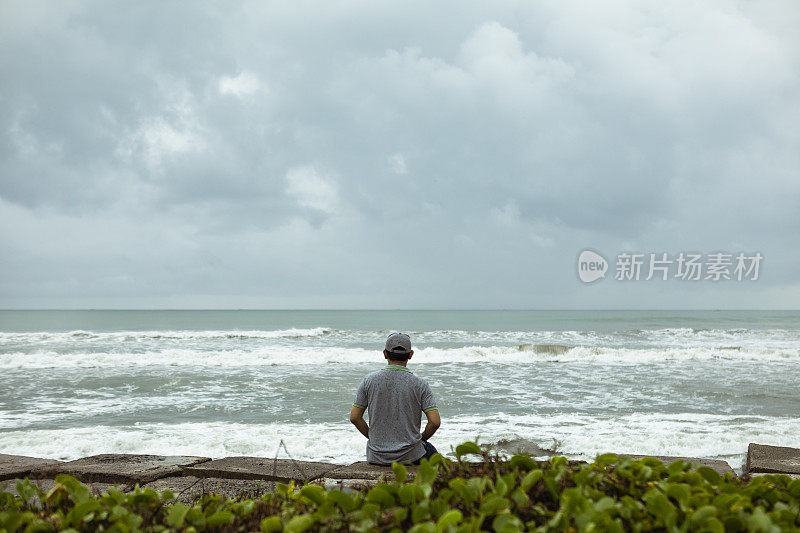 一个悲伤而孤独的人坐在印度洋前