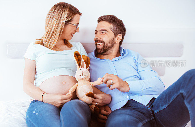 怀孕夫妇在家里感受到爱和放松。他们和洋娃娃一起玩