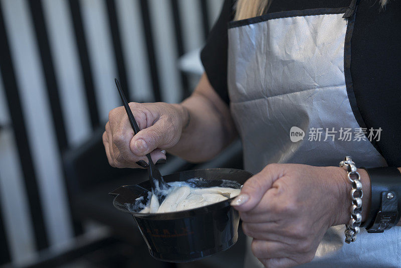 美发师在发廊搅拌染发膏的细节。新常态。