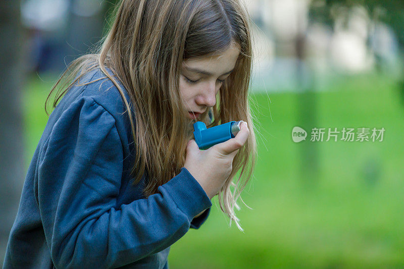 小女孩在公园里使用哮喘吸入器。